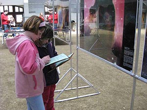 Photo of two girls on a scavenger hunt, standing in front of astronomy-related images.