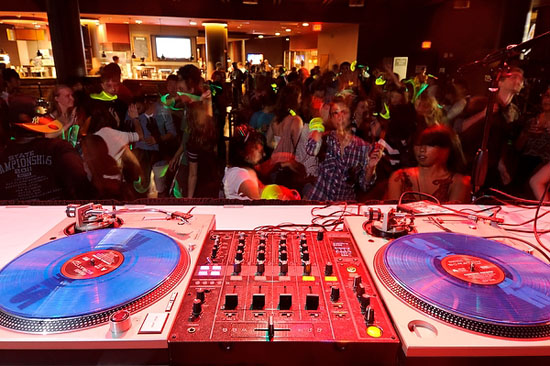 Photo of a DJ’s set up at the Sett, with students dancing in the background.