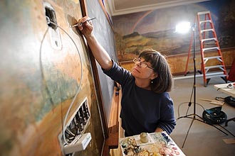 Photo of Joan Gorman repairing a mural.