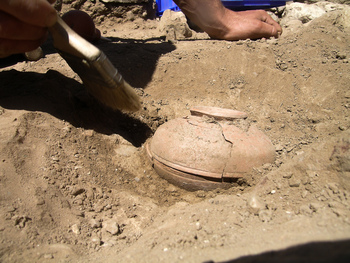 Photo: An inverted bowl, covering another bowl with a ritual deposit, emerges from the earth at Sardis.