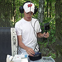 Photo of student using a transmitter with headphones to determine movements of transmitter-implanted fish.